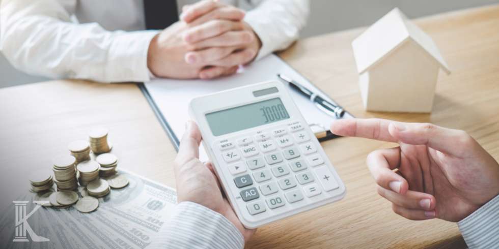 Dłonie trzymające kalkulator, w tle prawnik z umową kredytową