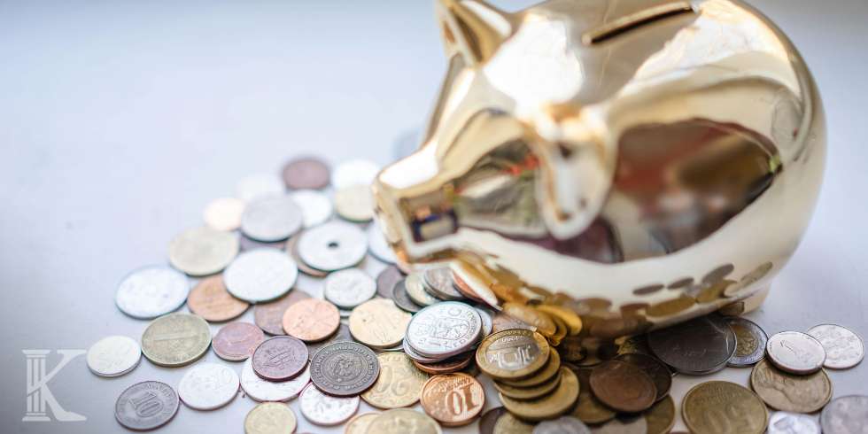 Złota świnka skarbonka i monety rozsypane obok