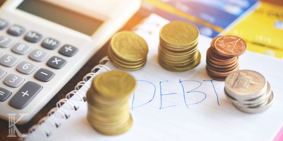 Kalkulator, monety i kartka z napisem DEBT - dług