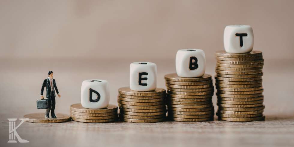 Stery monet, na nich klocki z napisem DEBT - dług
