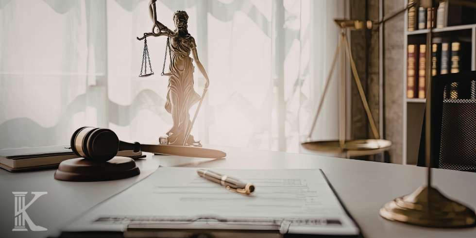 Law office desk with a scale of justice statue, a gavel, and legal documents on the forefront.