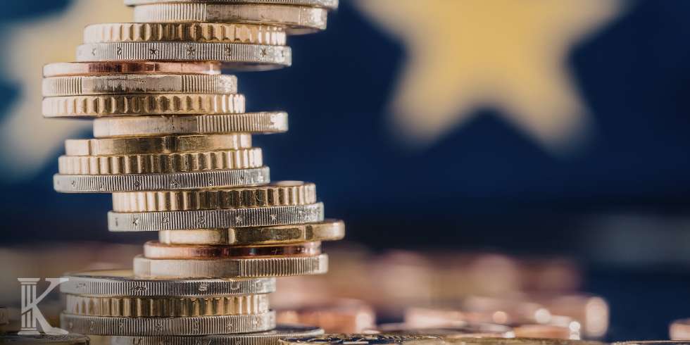 Tall stack of mixed coins balanced on a reflective surface, with a blurred starry blue background suggesting a patriotic or financial theme.