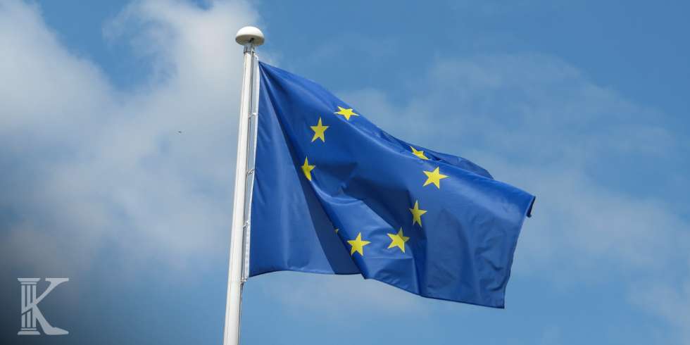 European Union flag waving on a flagpole against a blue sky.