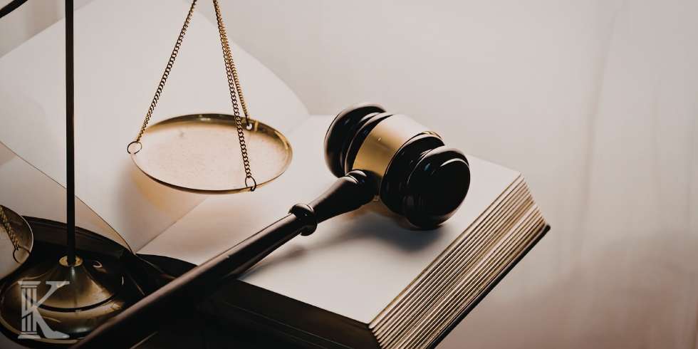 Gavel resting on an open law book with a balance scale in the background, symbolizing justice and legal proceedings.