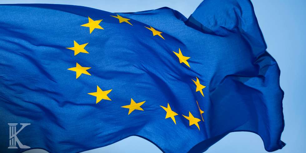 European Union flag waving in the wind, blue field with a circle of 12 yellow stars.
