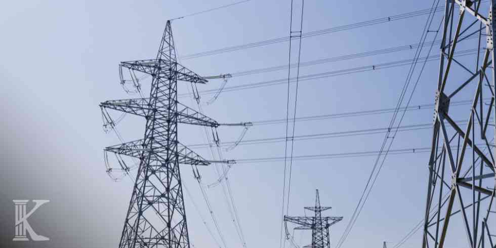 Młotek sędziowski na podstawce na biurku z dokumentami; w tle rozmyta postać prawnika.