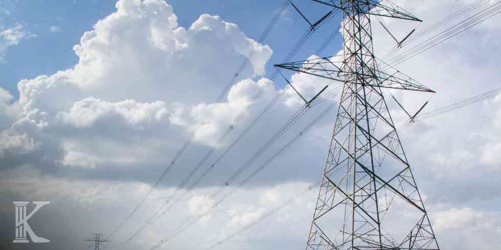 Kratownicowy słup elektroenergetyczny pod pierzastymi chmurami jako element nowej sieci przesyłowej.