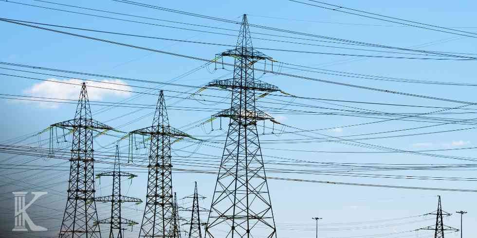 Krajobraz z licznymi słupami energetycznymi i gęstą siecią linii przesyłowych na tle jasnego nieba.