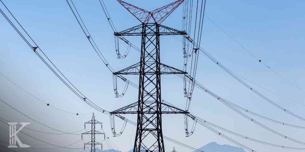 Stalowa konstrukcja linii energetycznej z przewodami przecinającymi niebo – inwestycja energetyczna na gruncie rolnym.