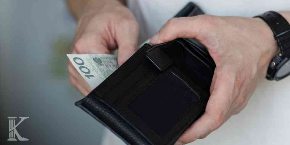 Mężczyzna wkłada banknot 100-złotowy do portfela – ilustracja odzyskiwania kosztów po całkowitej spłacie kredytu.