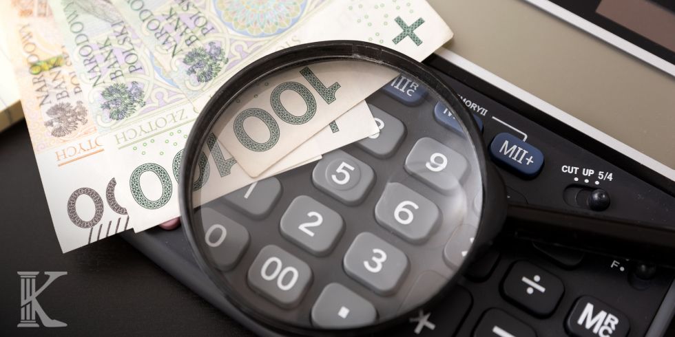 Polish zloty banknotes under a magnifying glass atop a calculator, signaling financial scrutiny or budgeting.