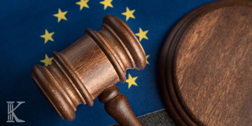 Wooden judge's gavel rests on a European Union flag backdrop, symbolizing EU law.