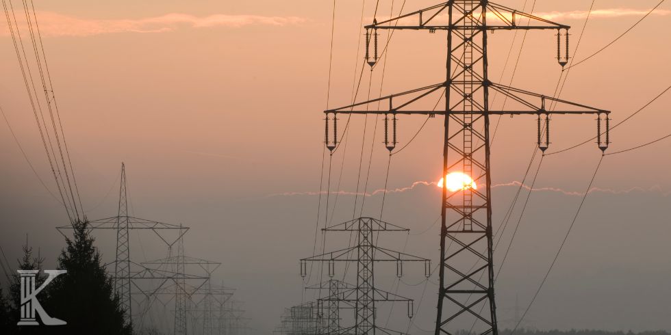 słupy energetyczne na gruncie, w tle zachód słońca