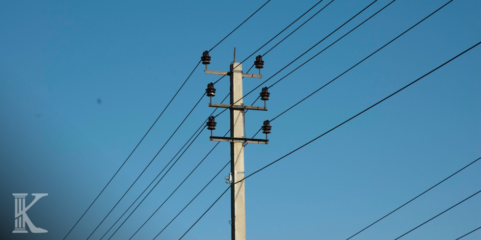 Słup elektroenergetyczny średniego napięcia z przewodami na tle bezchmurnego, niebieskiego nieba.